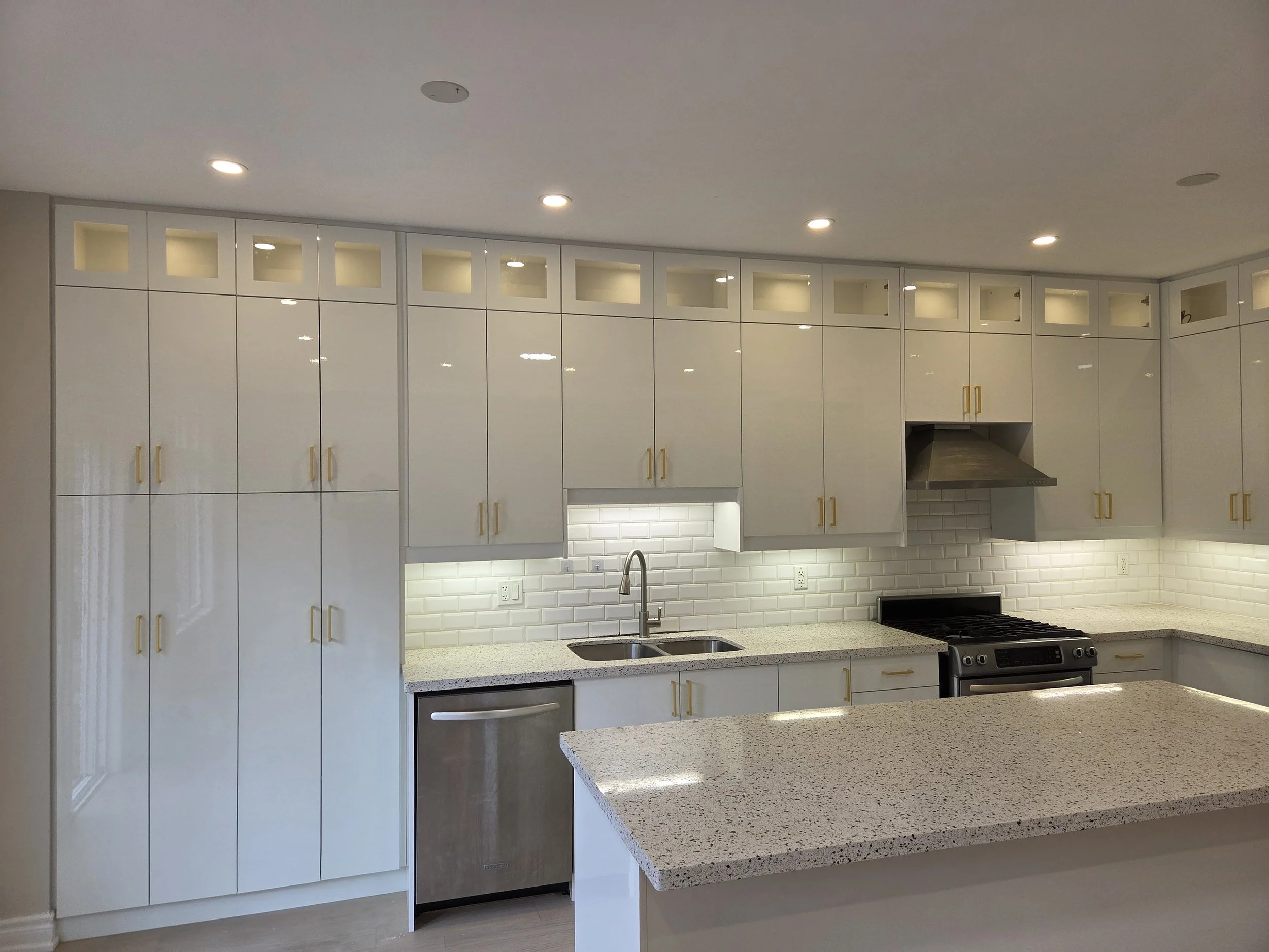 Modern kitchen with white cabinets, granite countertops, stainless steel appliances, and a white subway tile backsplash, illuminated by recessed lighting.