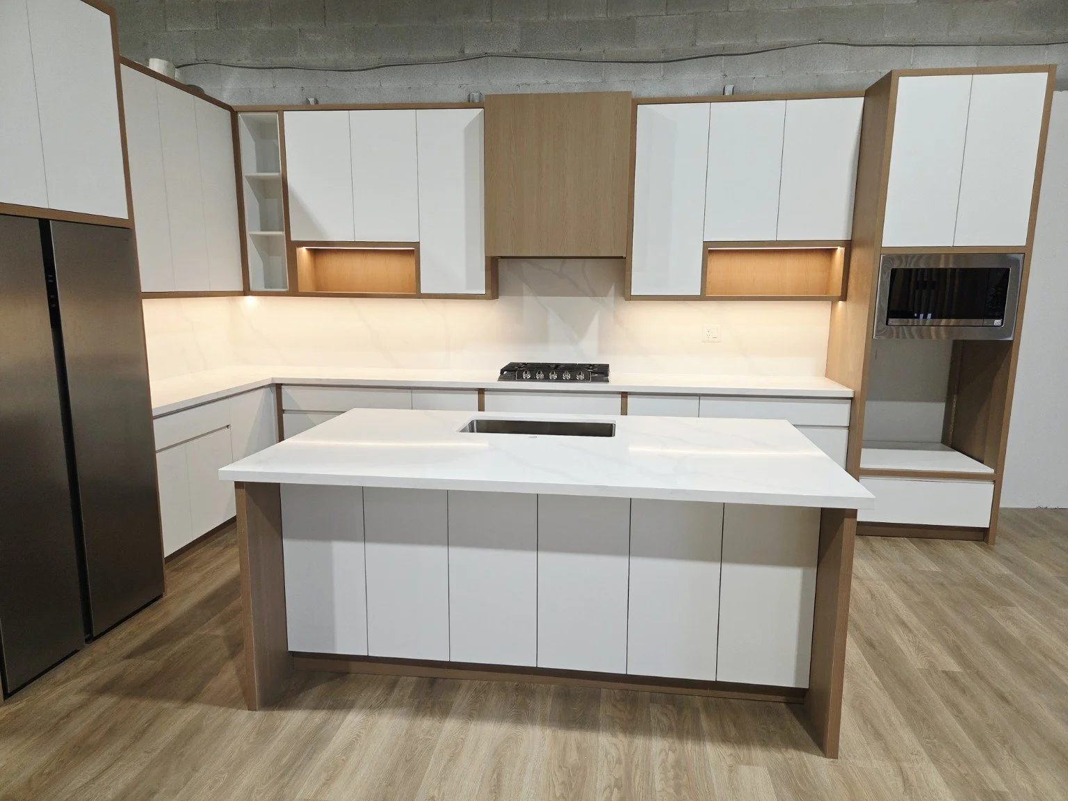 Modern kitchen with white cabinets, a center island, and built-in appliances including a microwave and stovetop.