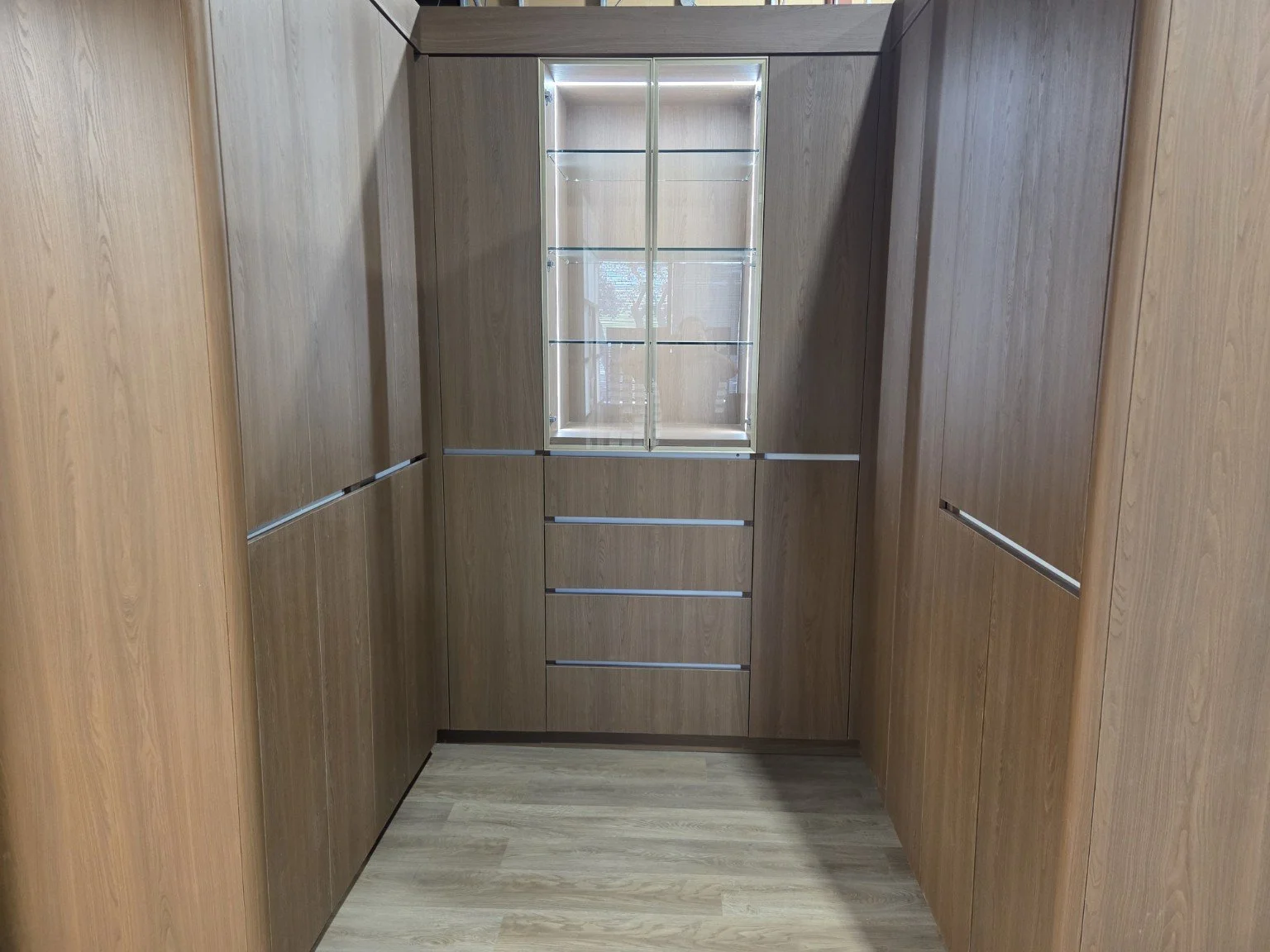 Interior view of a small wooden elevator with glass window at the top, wood paneling on the walls, and a wooden floor.