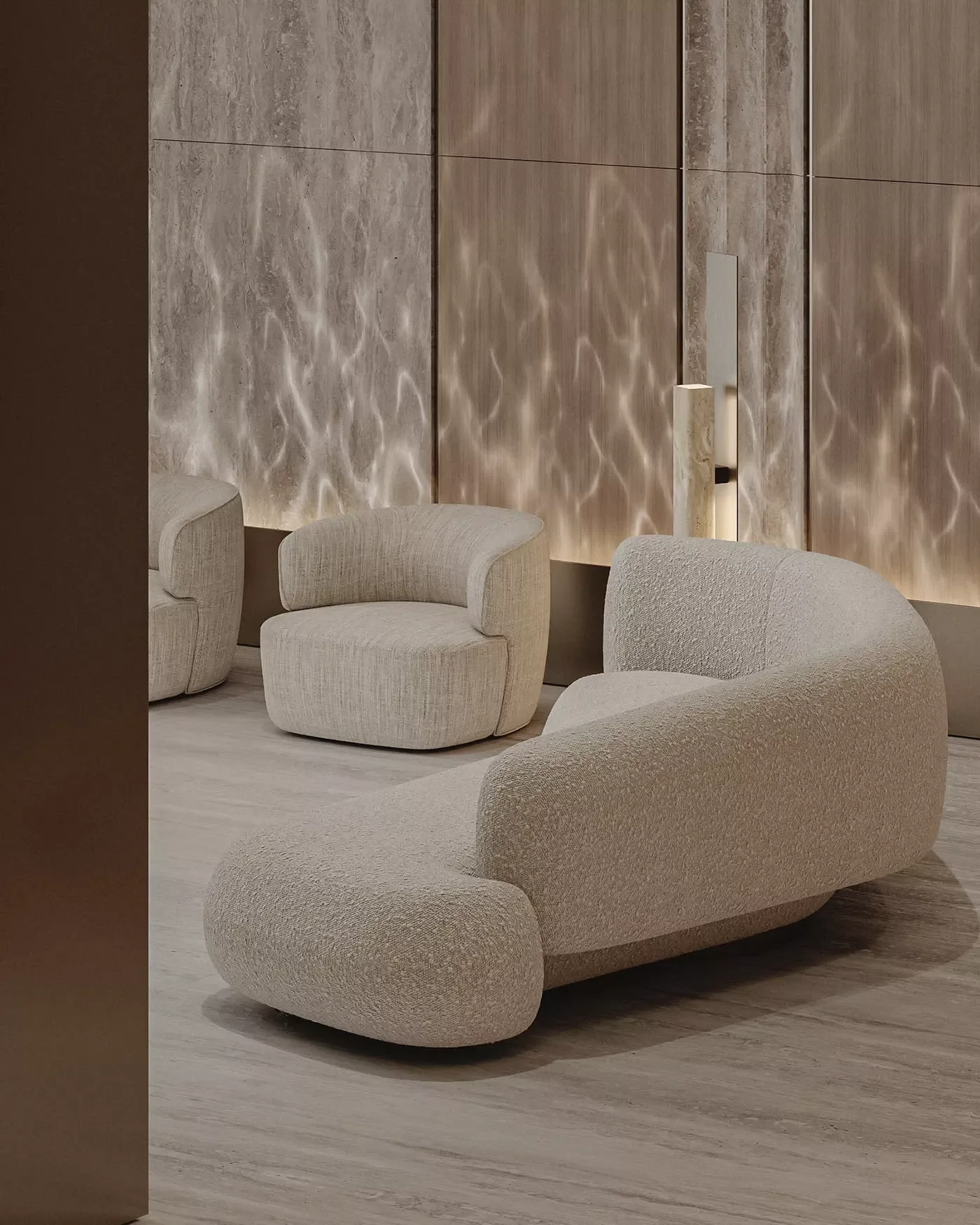 Modern lounge area with beige, textured seating and a stone textured wall with soft lighting.