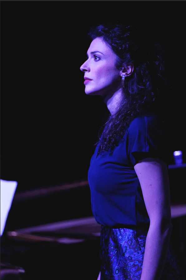 Femme jouant du piano dans un éclairage violet, vue de profil.