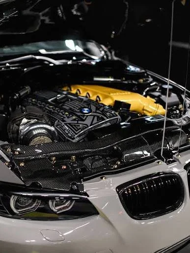Close-up of a BMW engine with a yellow engine cover, under the hood of a car.
