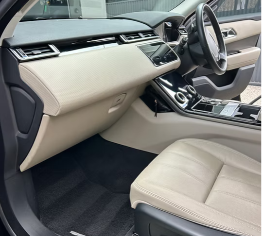 Interior of a modern vehicle showing the beige dashboard, center console, gear shift, and front passenger seat.
