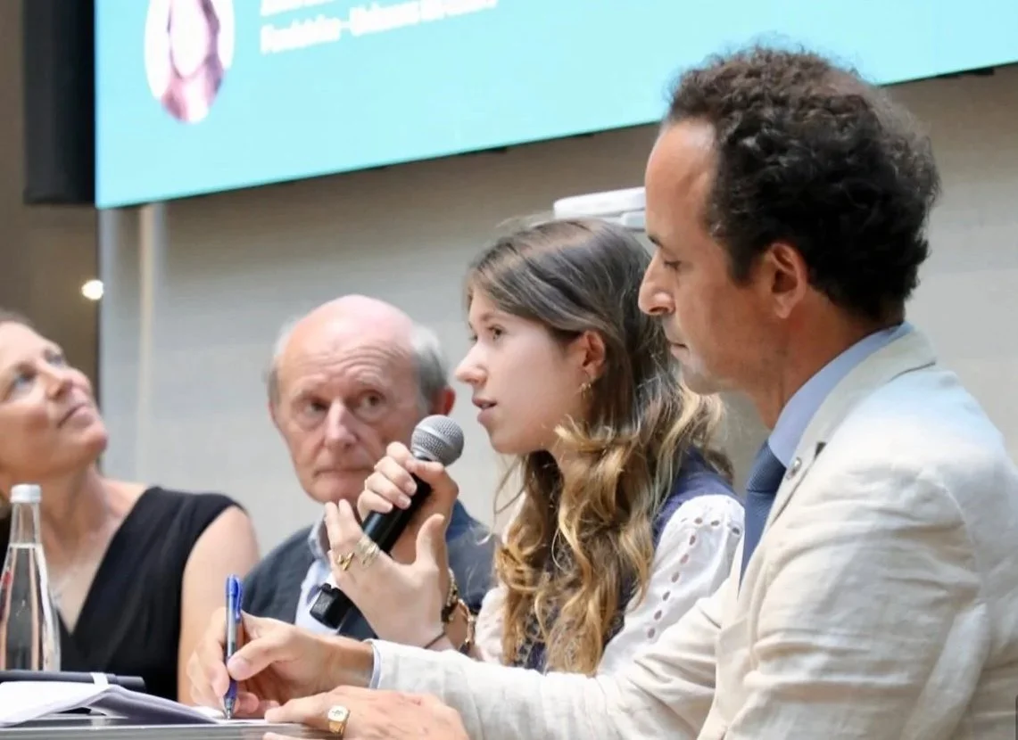 Un groupe de personnes participe à une discussion lors d'une conférence. Une femme parle dans un micro, un homme à côté la regarde attentivement, deux autres personnes écoutent.