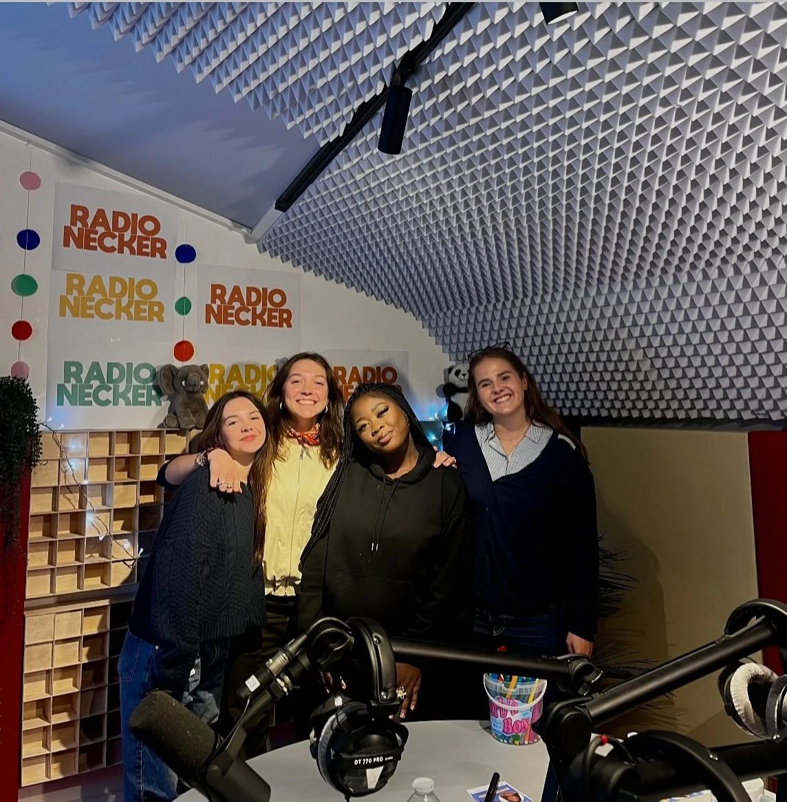 Quatre femmes souriantes posent dans un studio de radio Radio Neckar, décoré de mascottes et panneaux avec le logo.