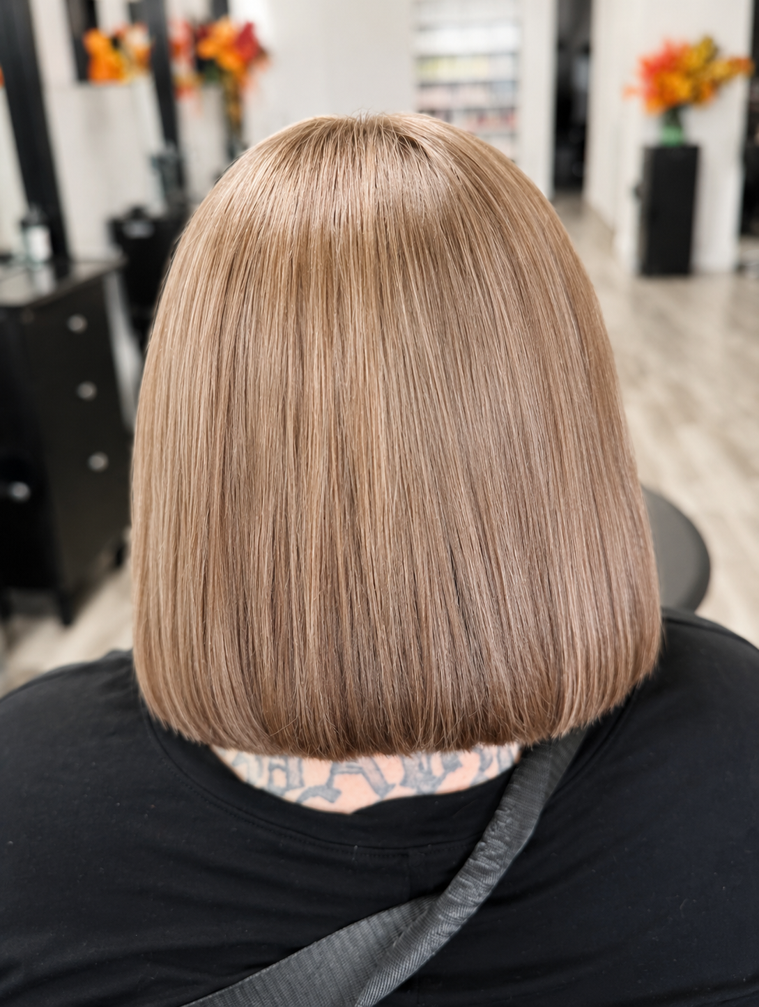 Rear view of a person with straight, shoulder-length, light brown blonde hair in a salon.