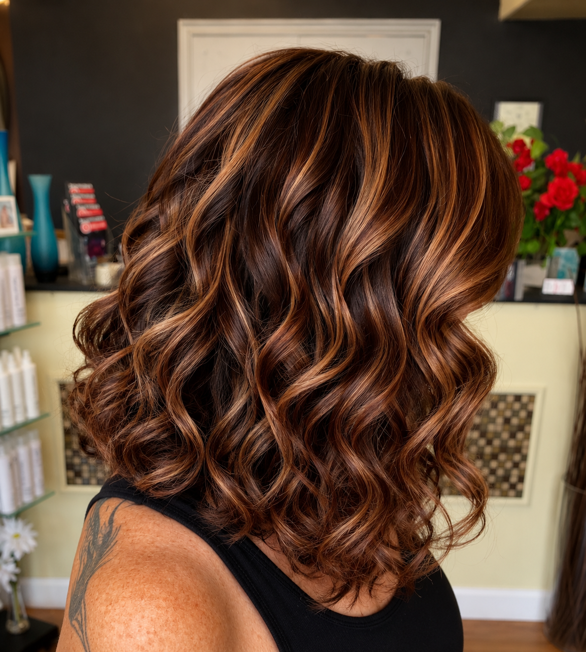 Woman with shoulder-length, curly, layered hair with caramel and chestnut highlights.