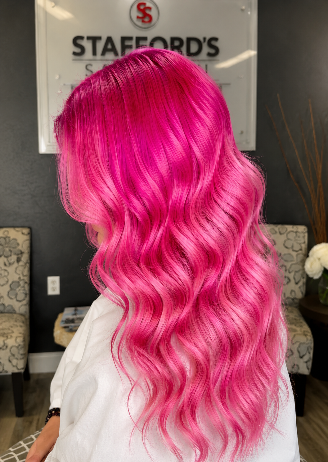 Person with long, wavy, bright pink hair in a salon setting.