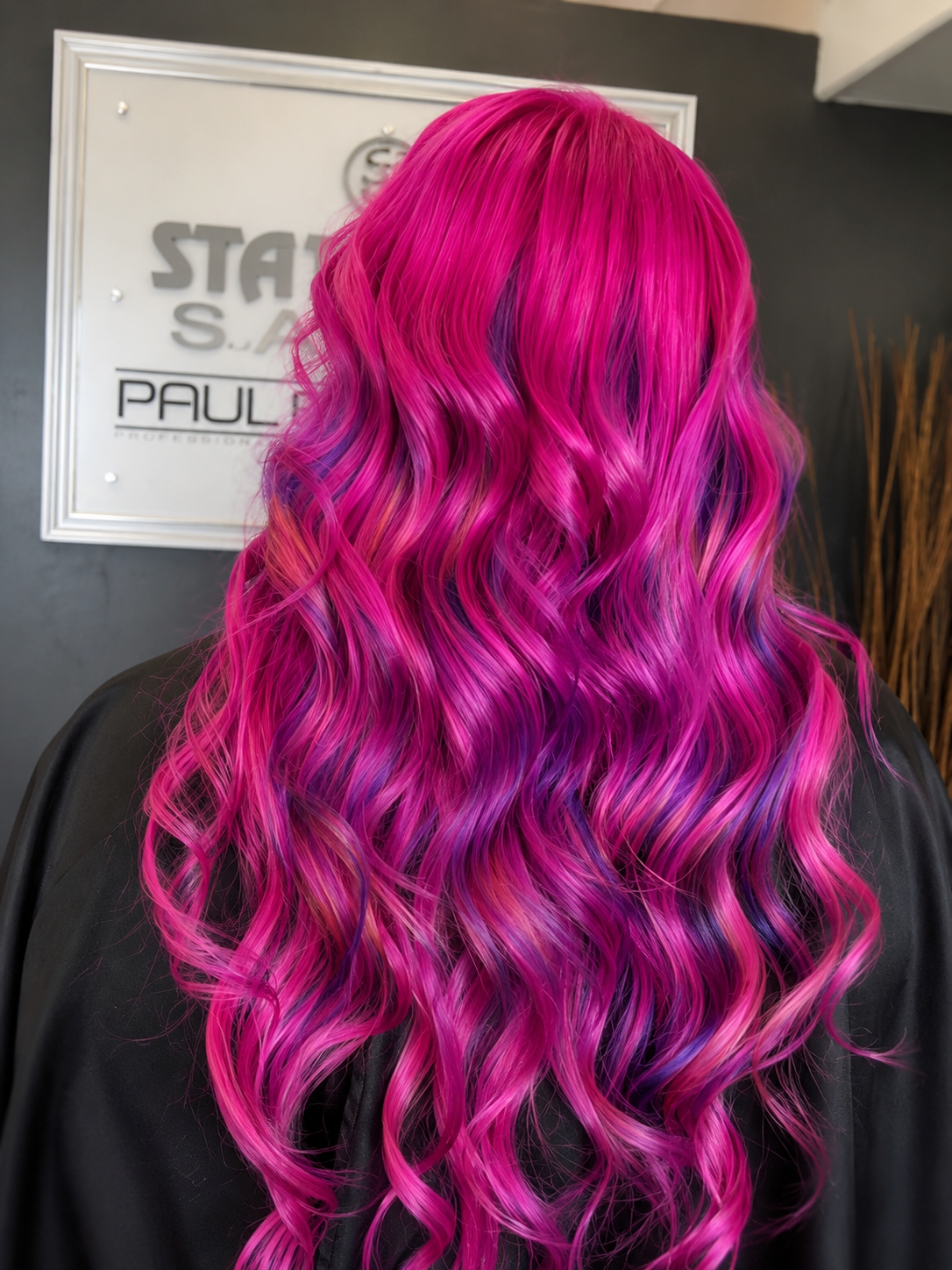 Back view of a person with long, wavy, bright pink and purple hair.