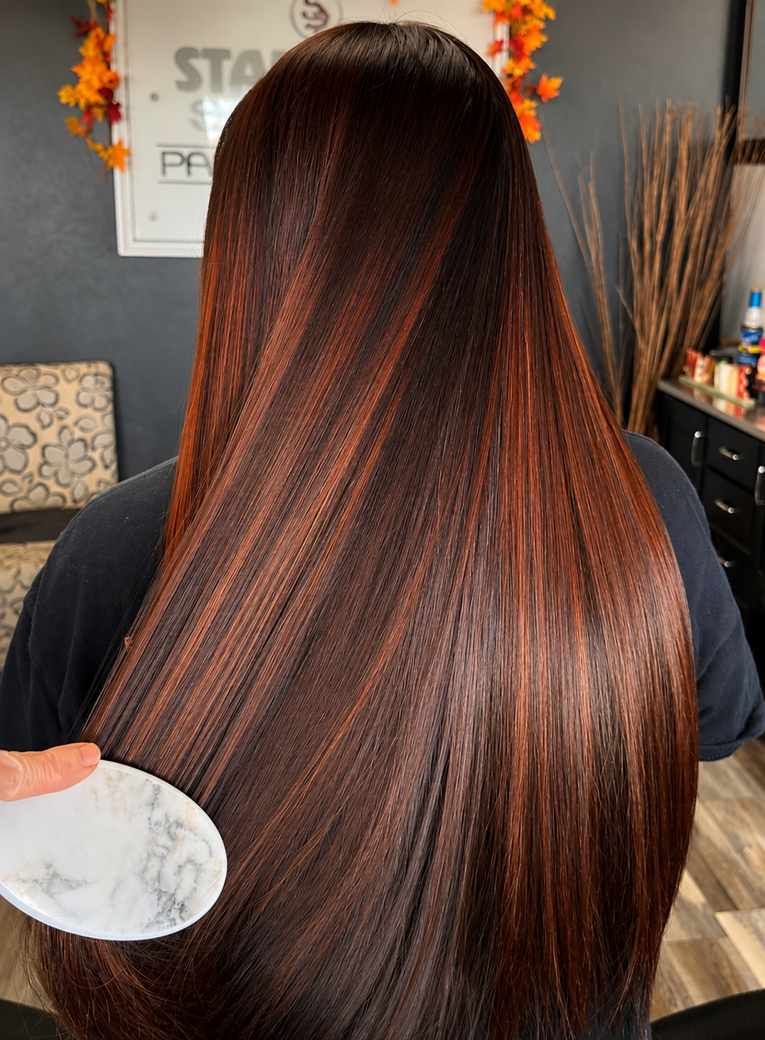Person with long, shiny, and smooth reddish-brown hair in a salon setting.