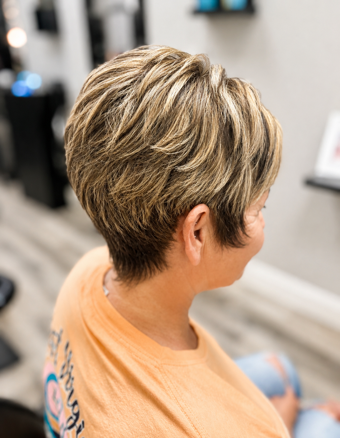 Close-up of a person's short, layered, blond hairstyle from the side in a salon.