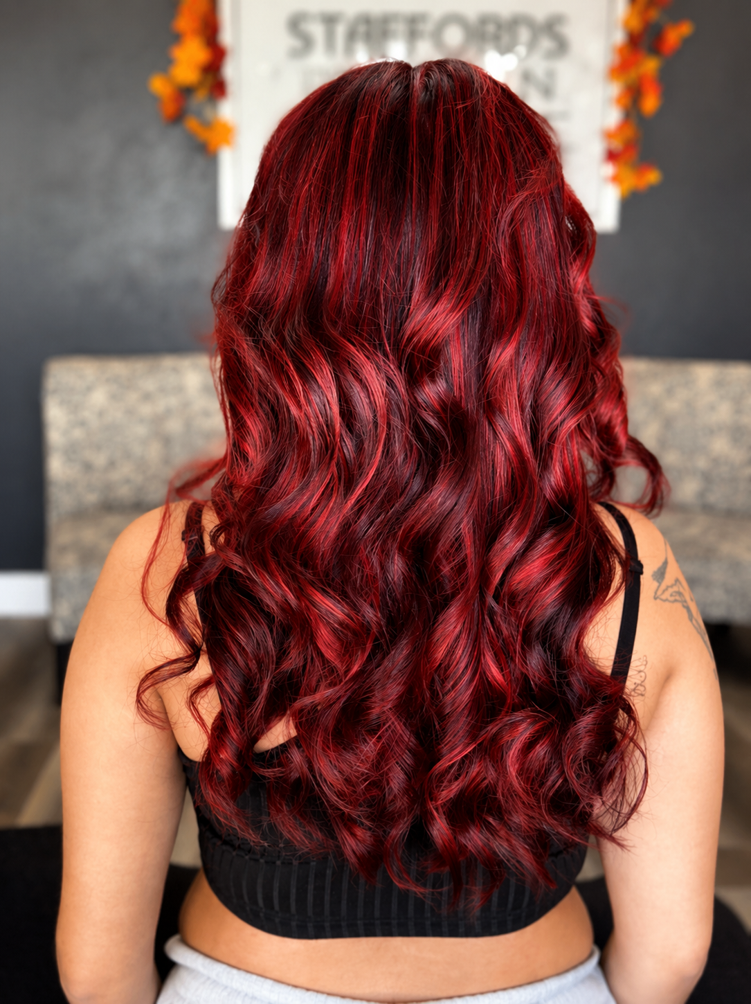 Back view of a woman with long, wavy, red hair.
