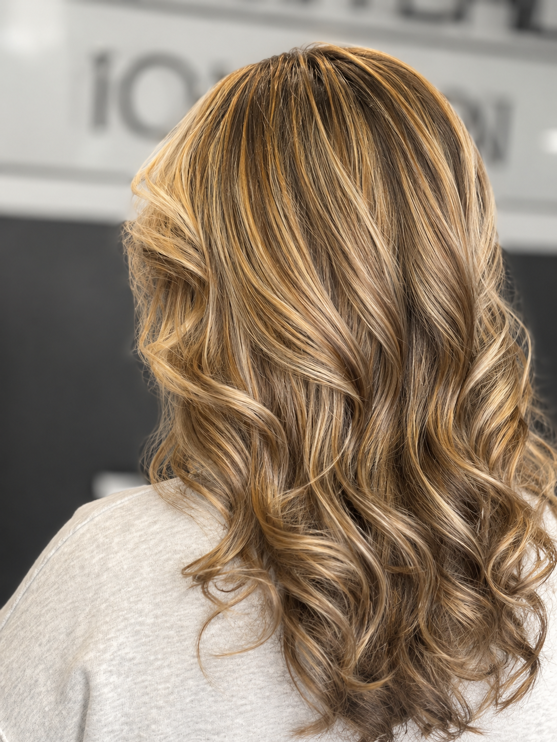Back view of a woman with shoulder-length, blonde, curly hair.