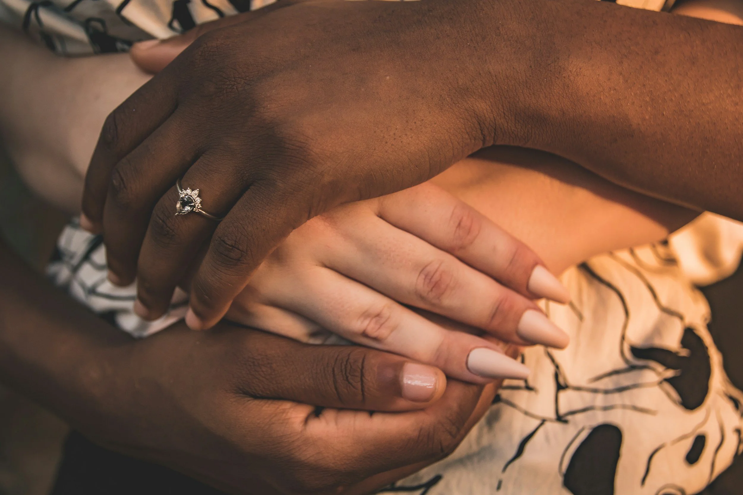 Close-up image of two hands with different skin tones gently touching.
