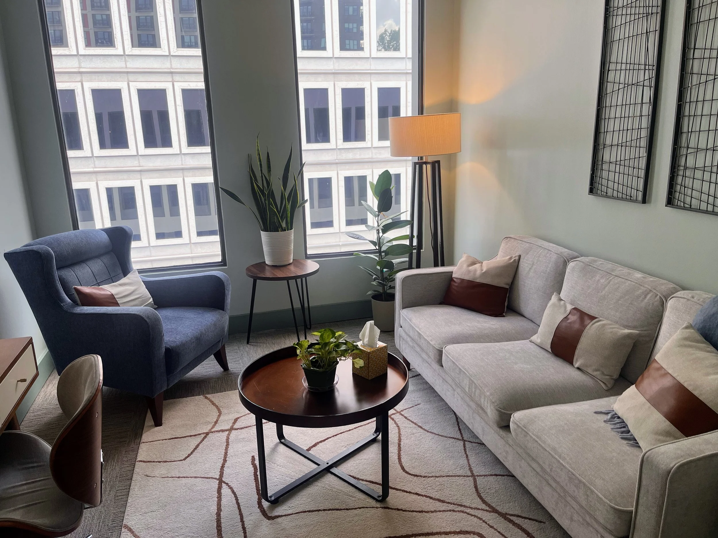 Sunlit therapy office with green plants near a window, creating a warm and inviting space.