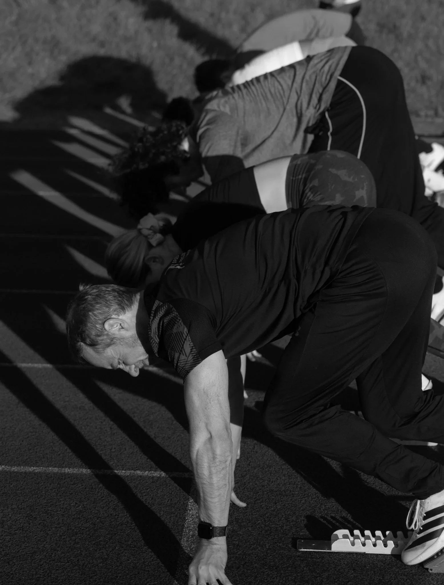 A person in athletic clothing doing block starts on a track.