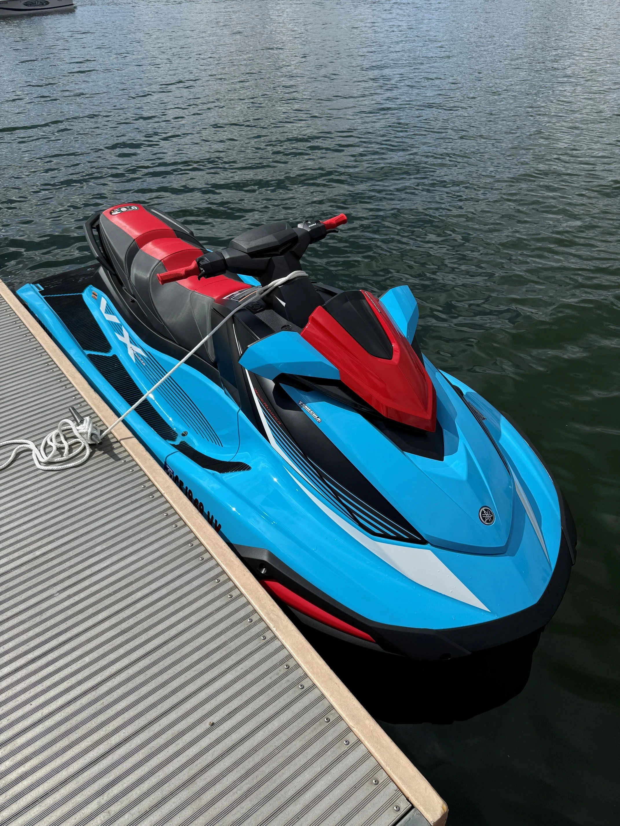 A blue and red jet ski tied to a dock on a body of water.