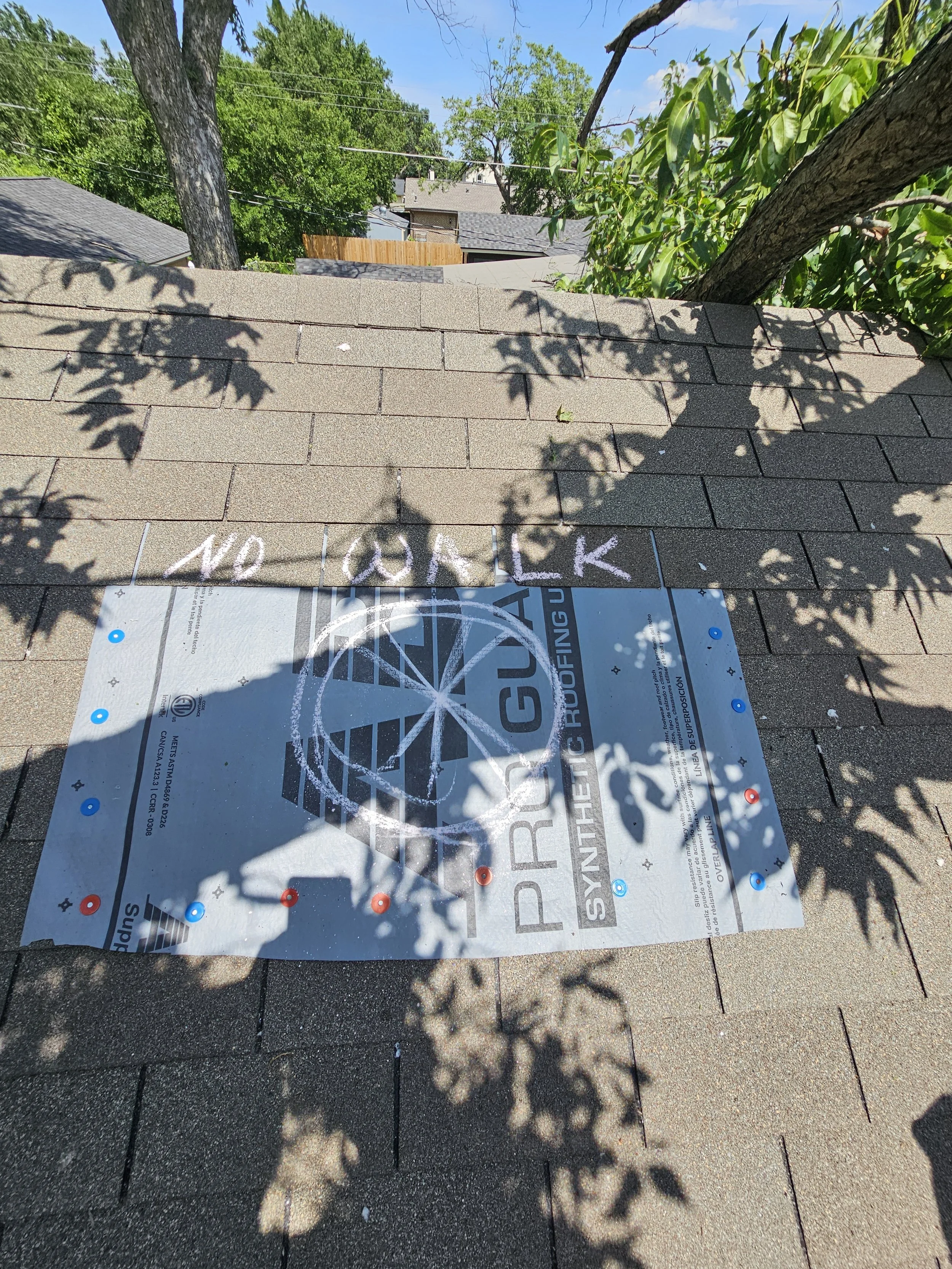 Shaded rooftop with a piece of insulation material and the words 'NO OAK' written in chalk on the roof surface.