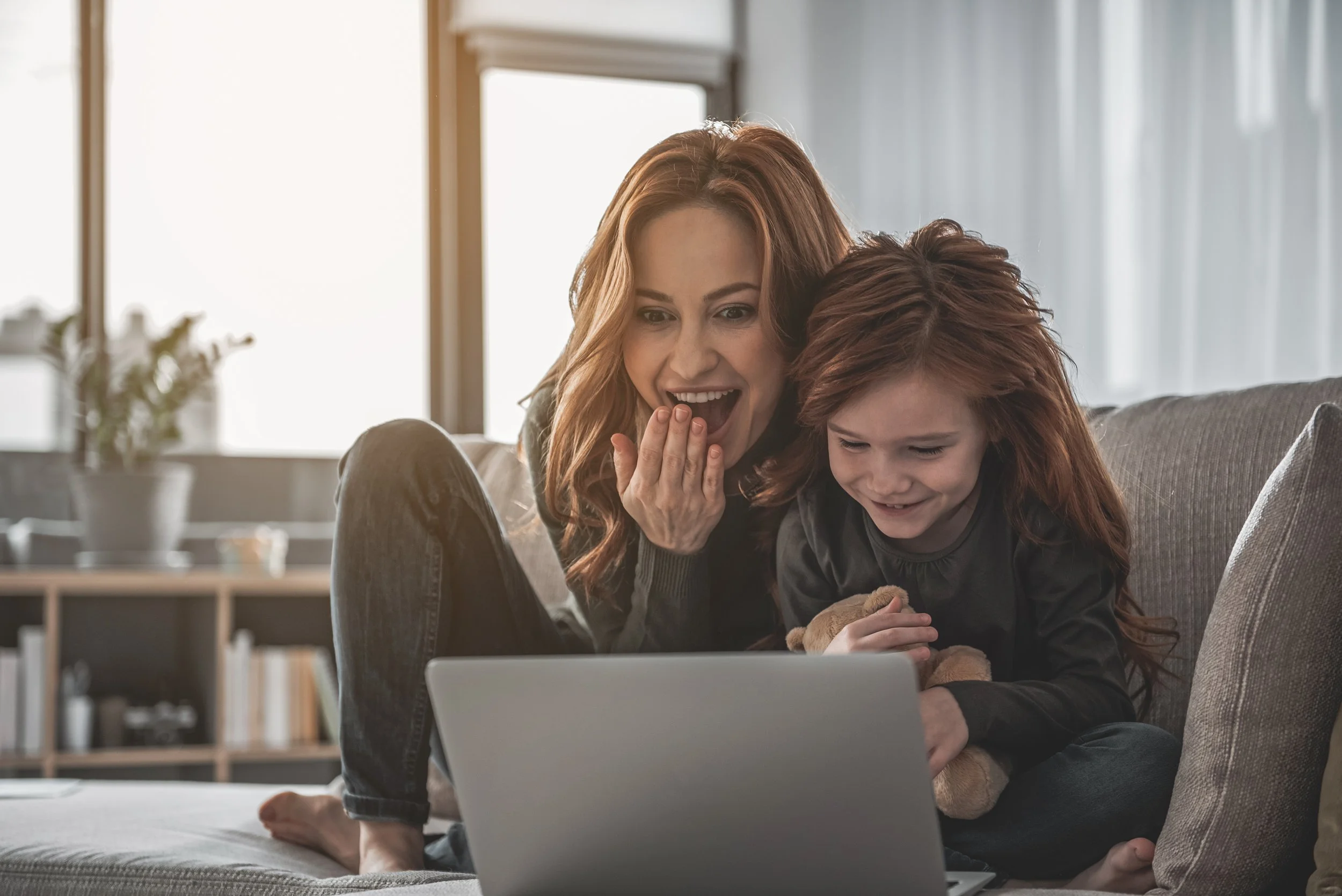 Photo of a mother and daughter smiling while looking at a laptop screen
