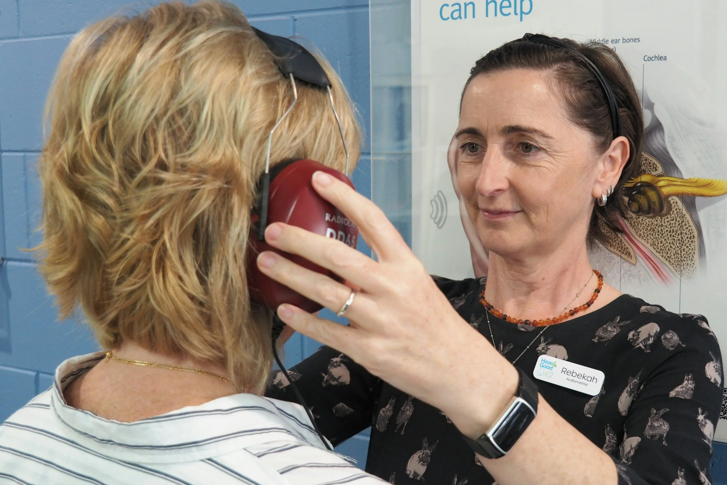 An audiologist placing headphones on a patient getting ready for a hearing test.