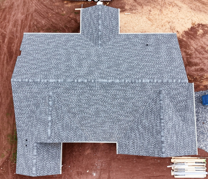 A building under construction with a roof covered in gray shingles, taken from above.
