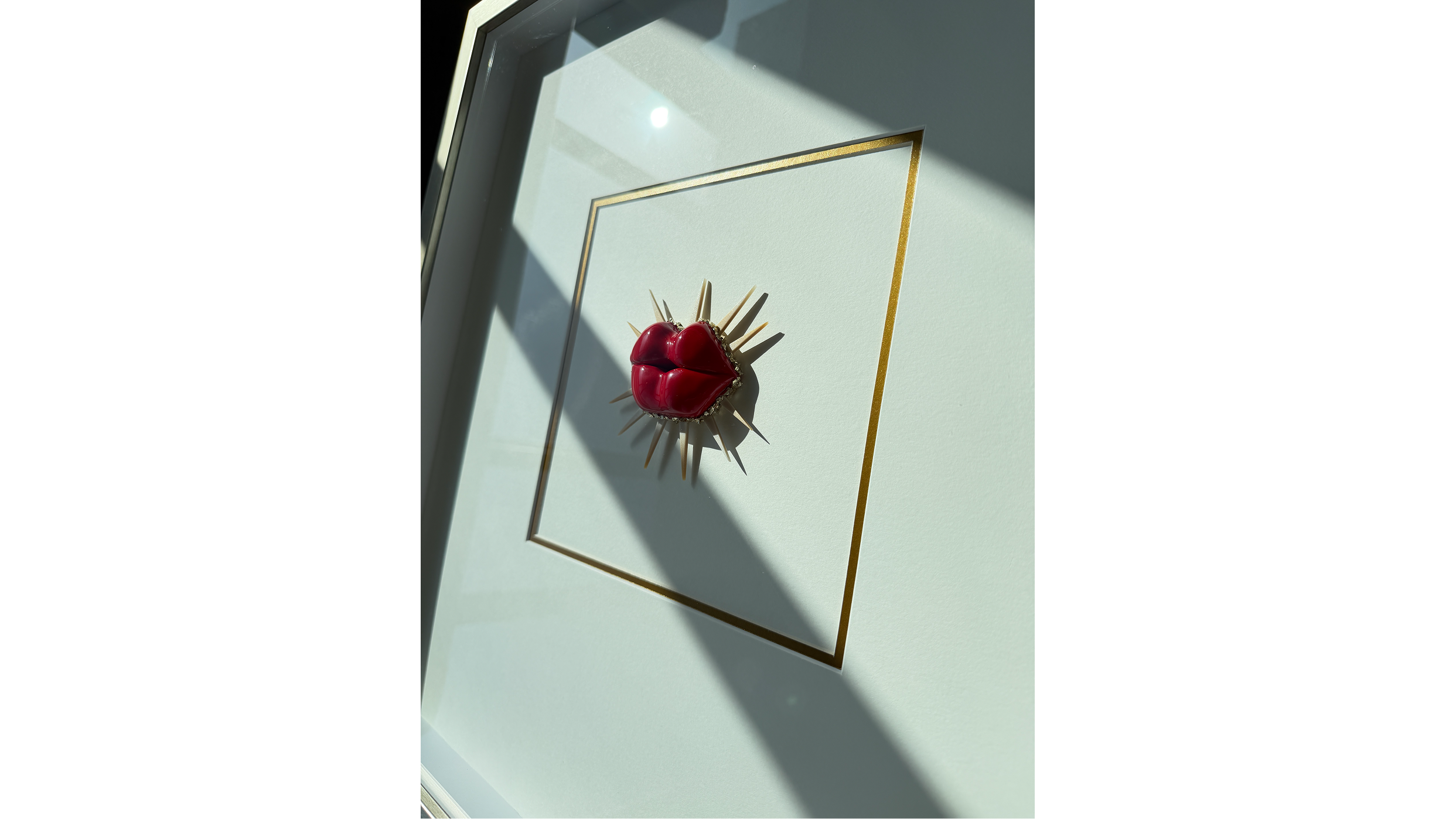Decorative framed art with heartbeat shape and spikes, illuminated by sunlight.