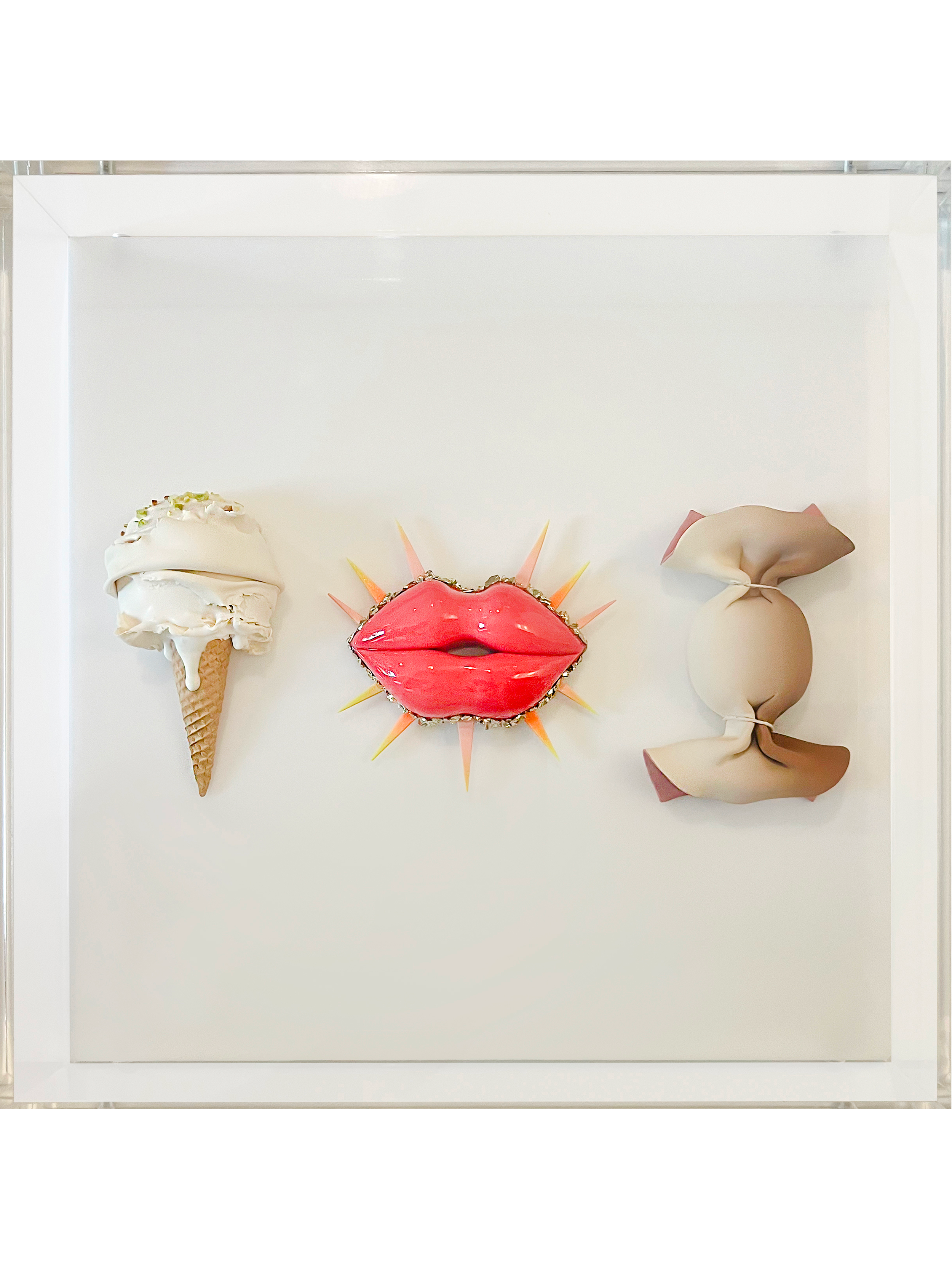 Mixed media artwork featuring an ice cream cone, a red lips face, and a beige and pink abstract shape, all mounted on a white background in a white shadow box frame.
