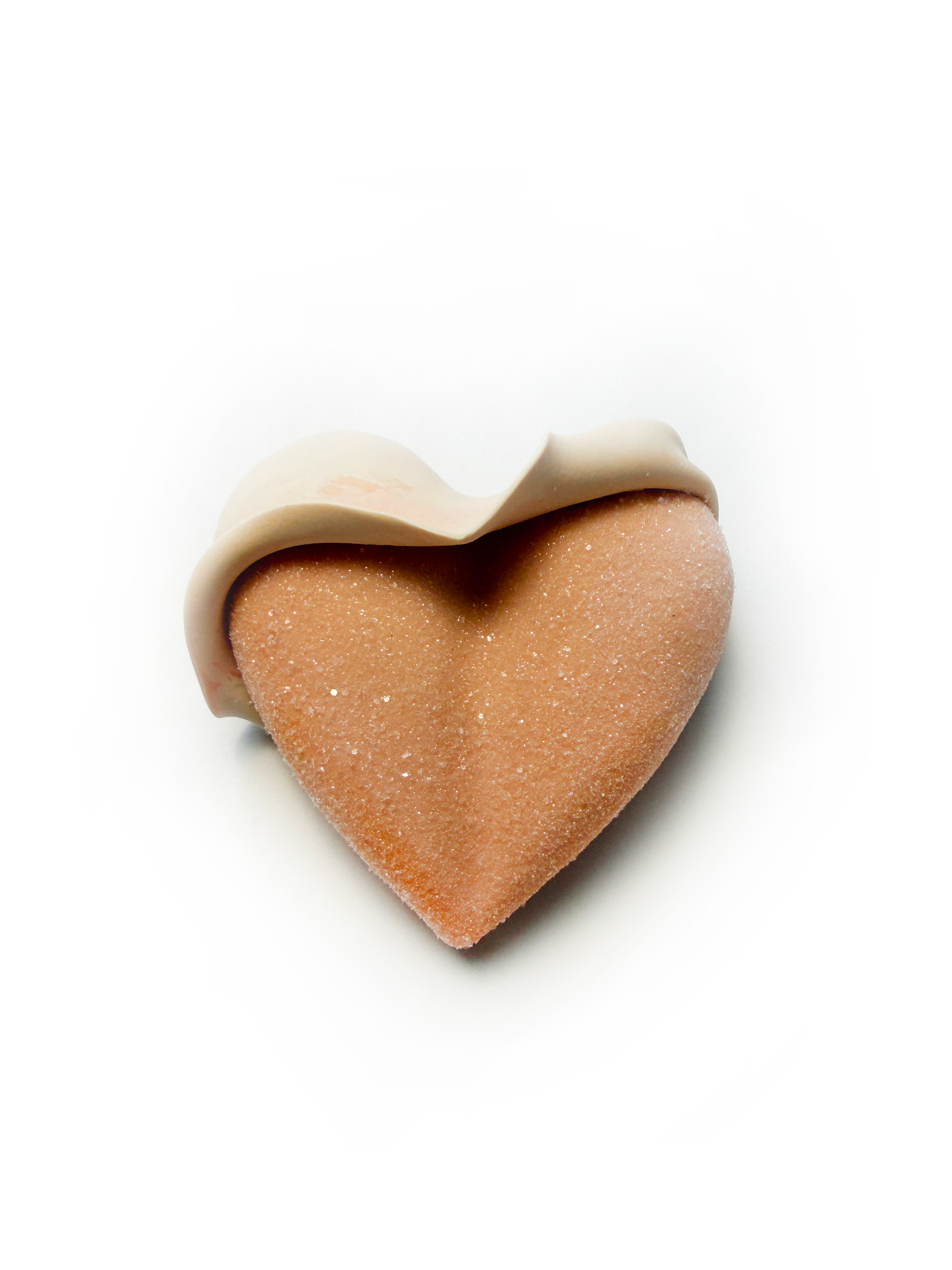 A heart-shaped cookies with a pink sugar coating, topped with a white chocolate curl.