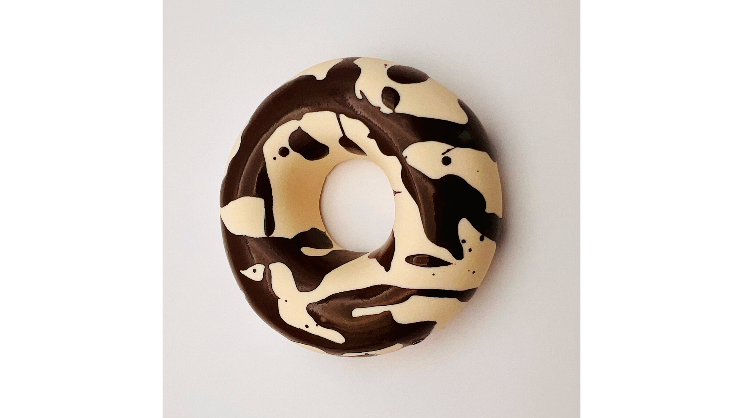 Decorative donut with black and white swirl icing on a white background.