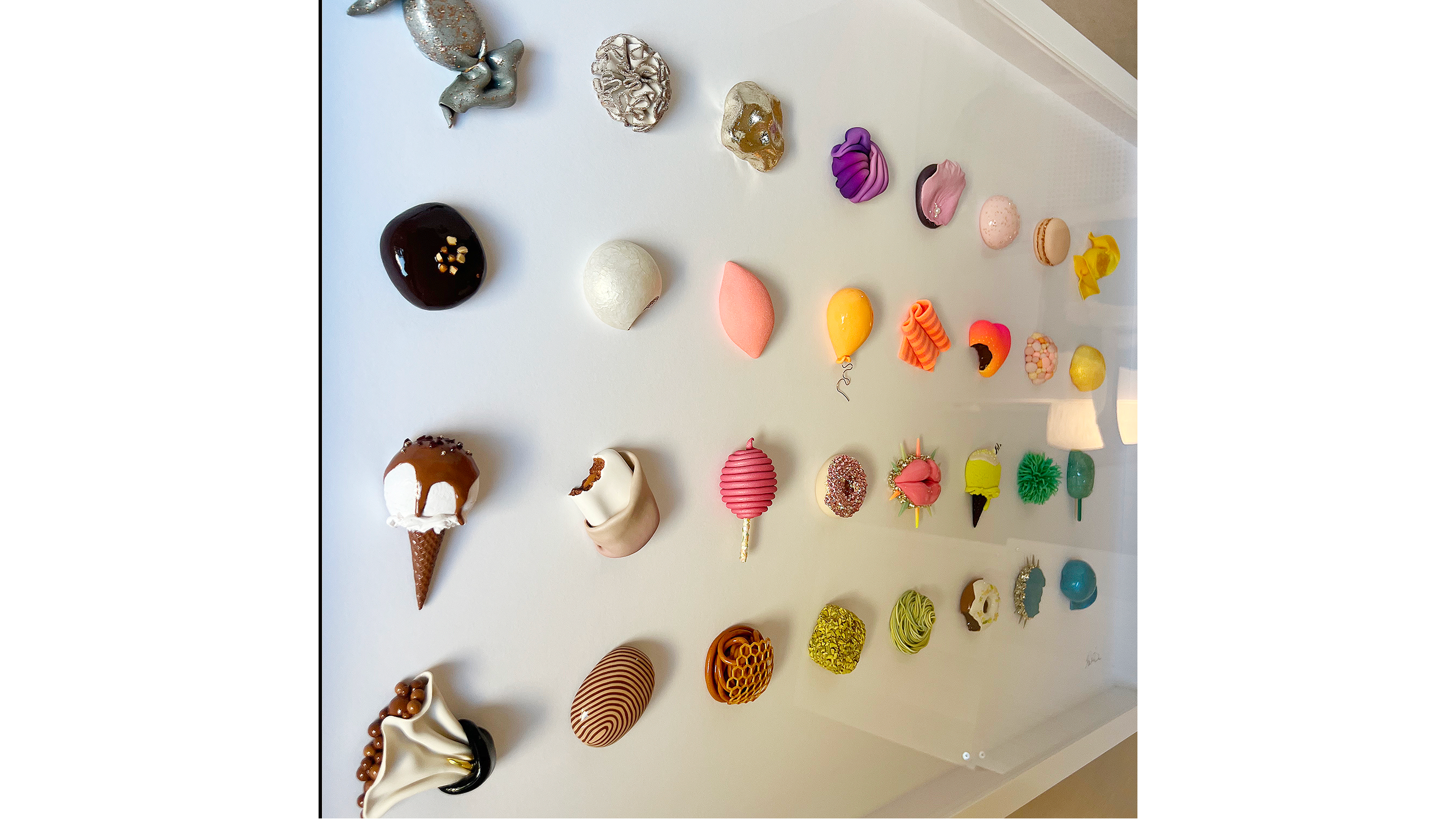 A variety of colorful decorated desserts and confections arranged on a white surface, including candies, chocolates, and small cakes.