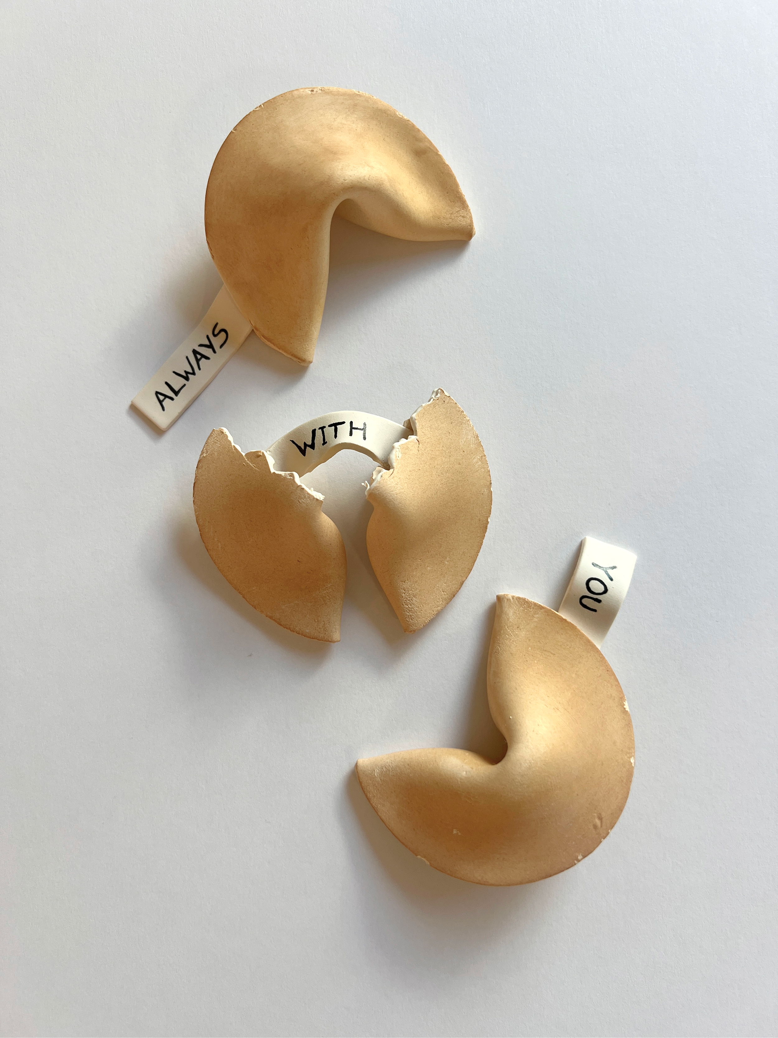 A broken fortune cookie with a note inside that says "WITH" and a separate note that says "YOU."