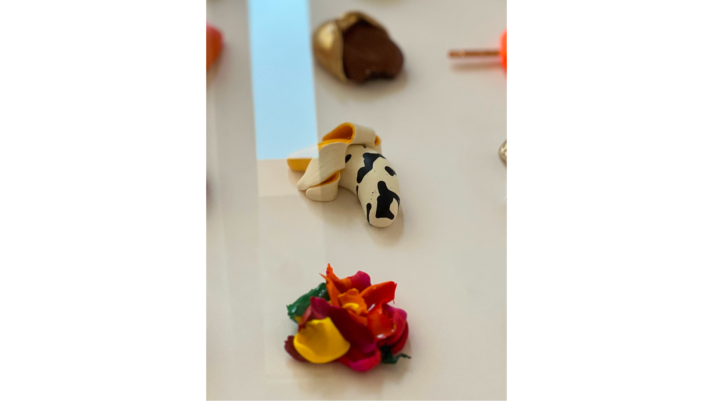 Colorful flower-shaped objects arranged on a white surface with a small figurine of a dog in the background.