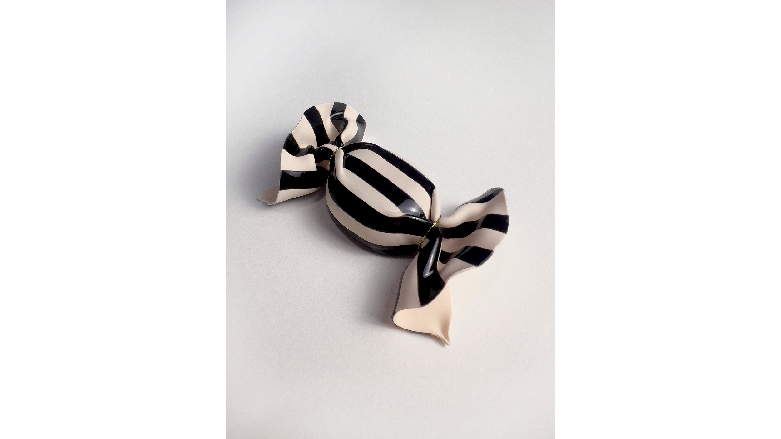 A black and beige striped ribbon tied into a decorative bow on a white background.
