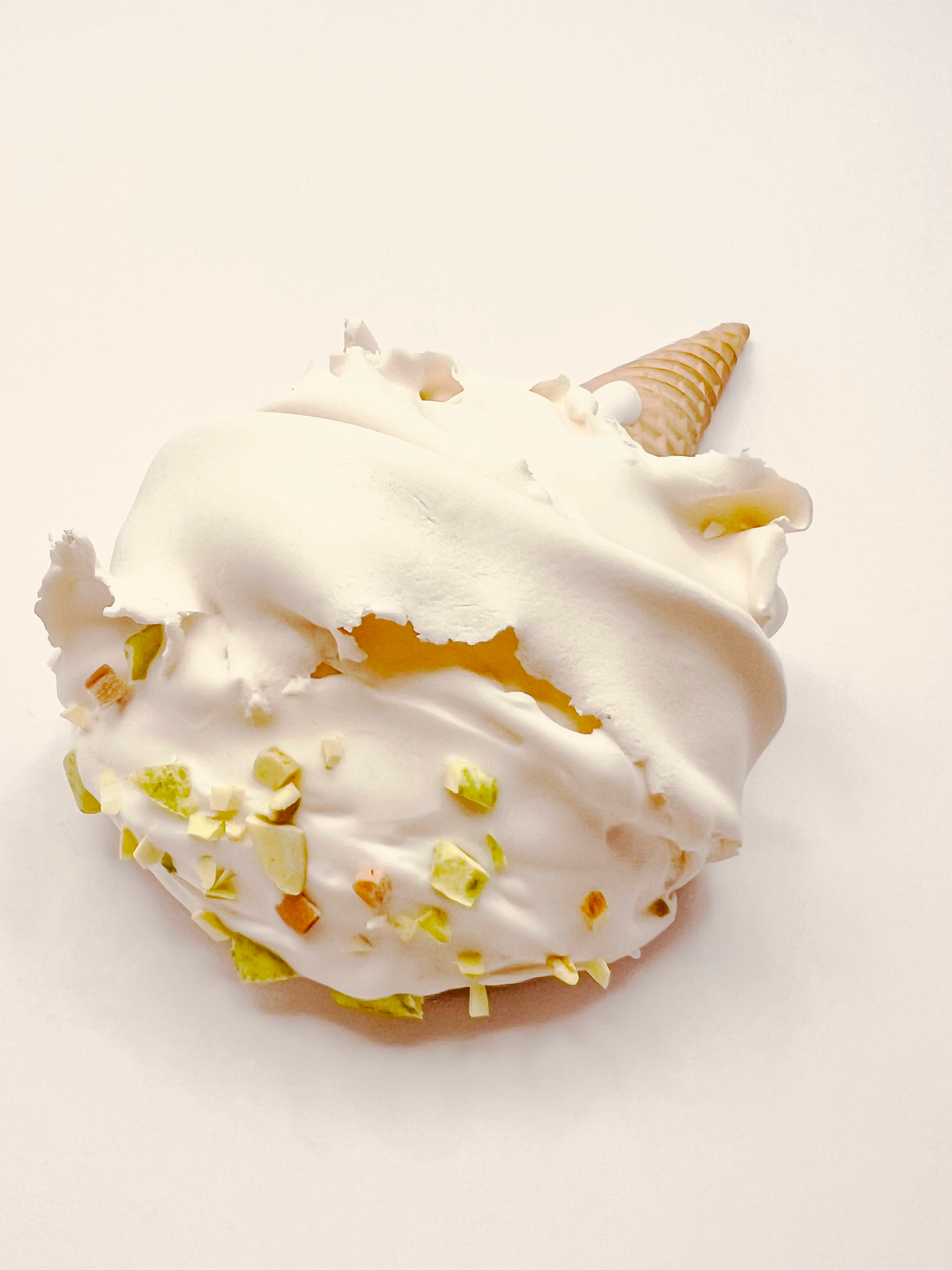 A dessert with white whipped cream topped with chopped nuts and an ice cream cone.