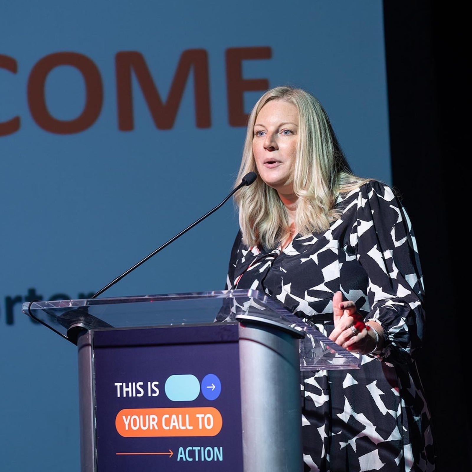 A women speaking at a conference from the podium.