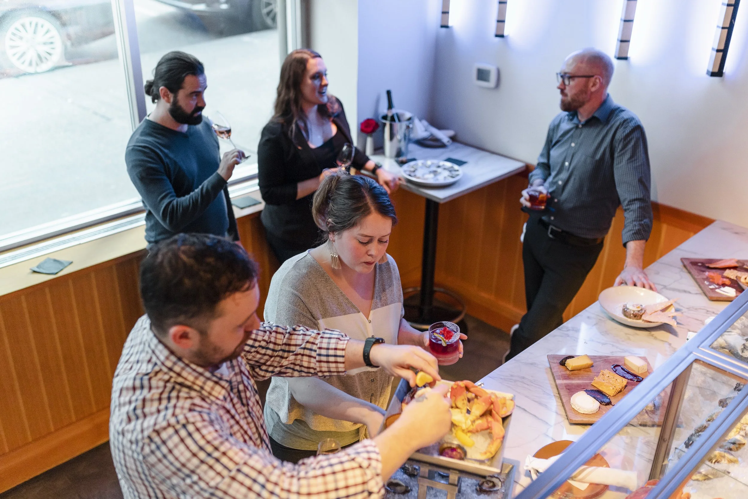 Group of people enjoying food and drinks at a buffet in a cozy indoor setting.