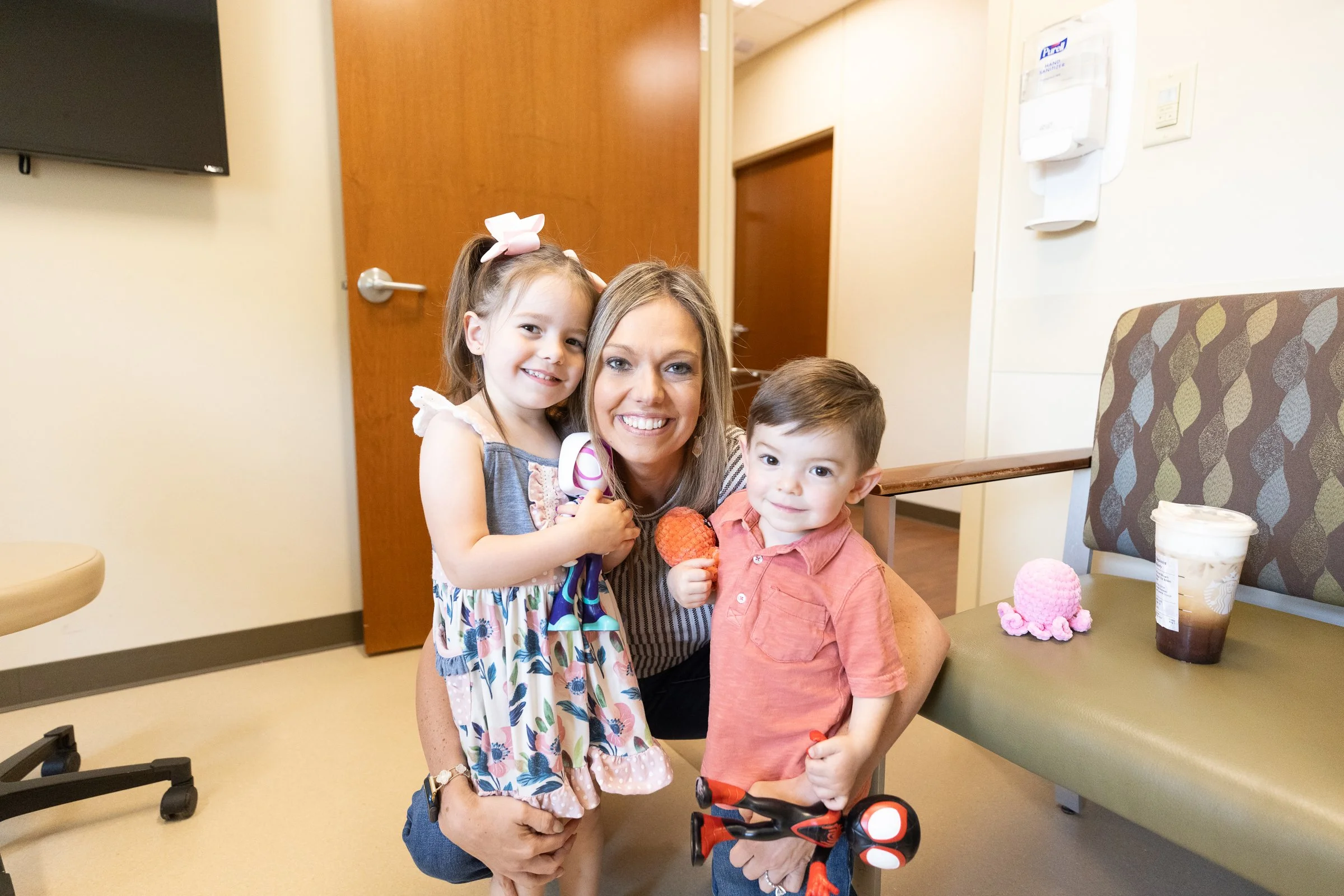 A woman, Tia, the owner of The Reserve and two of her children smiling and posing for a photo in the SIU Medicine ENT Clinic where Tia works full time through the week.