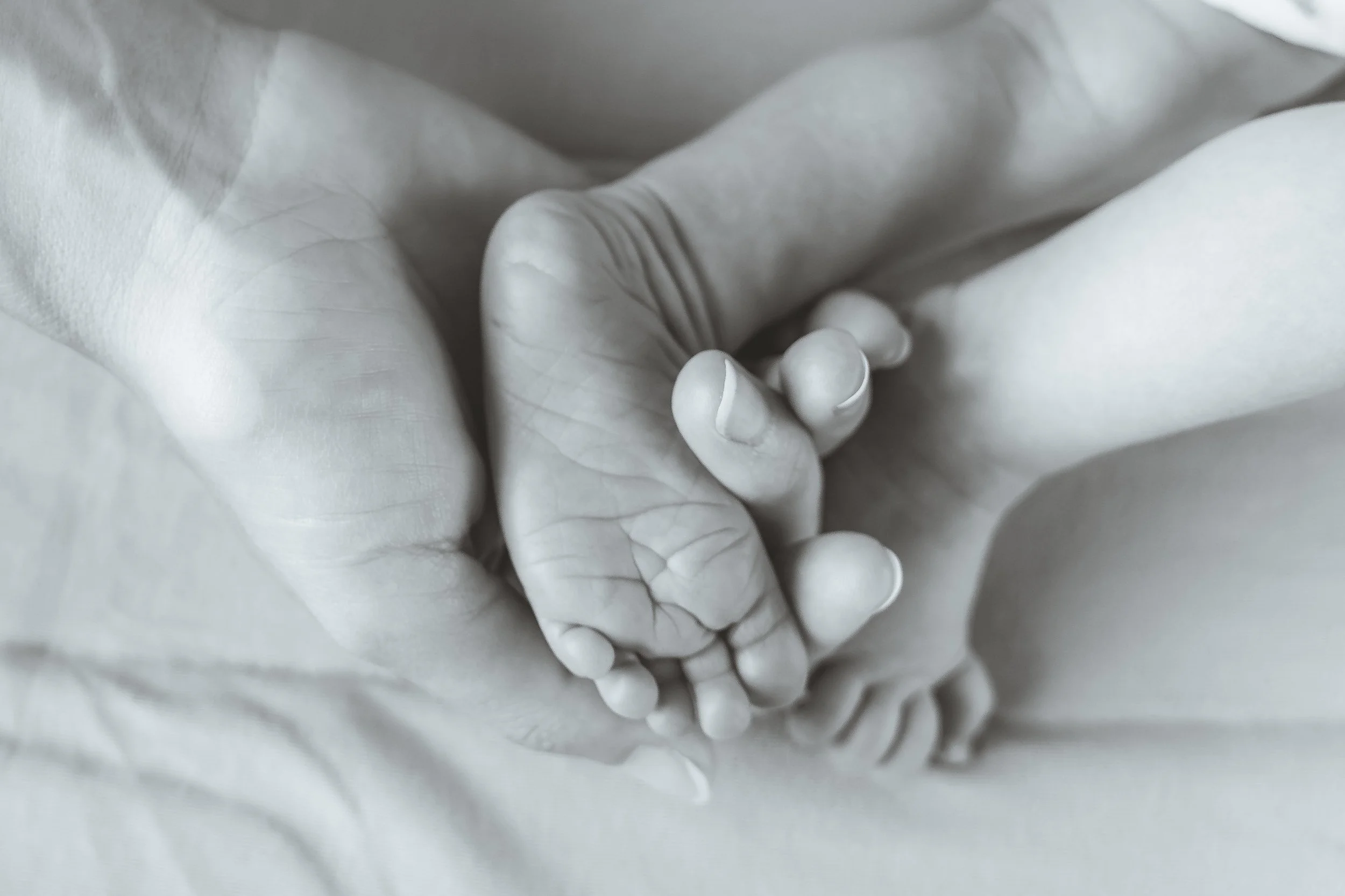 Close-up of two hands holding each other, with a paper-like texture in the background.