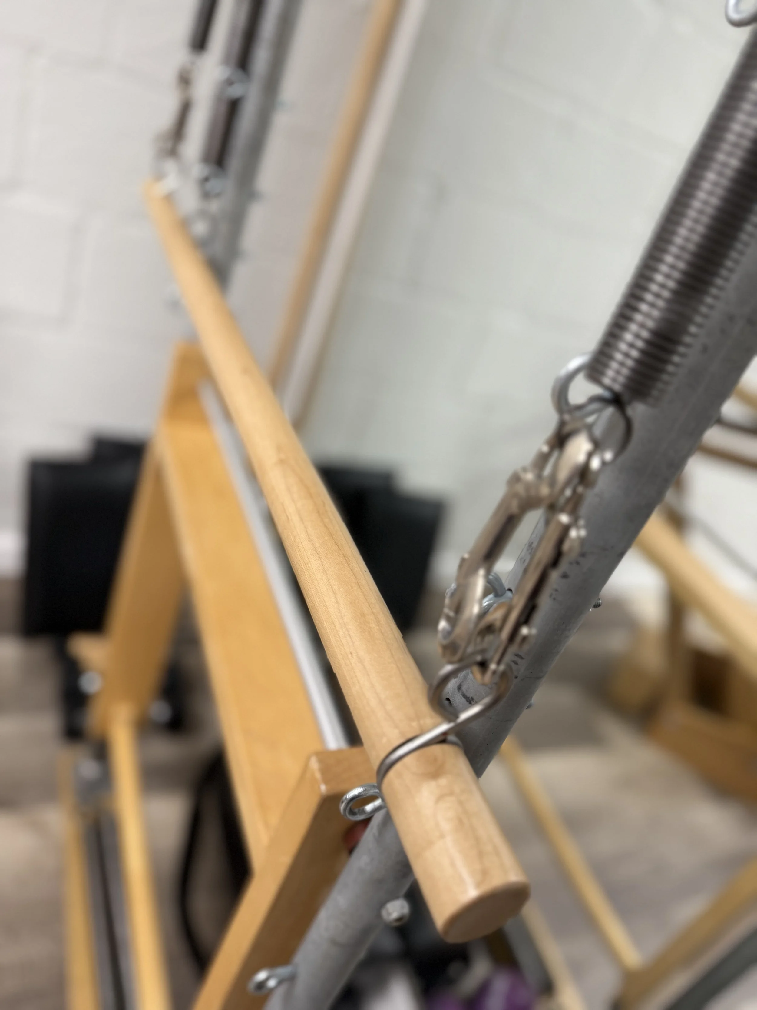 Close-up of a Pilates Tower with a metal spring clamp attached to it.