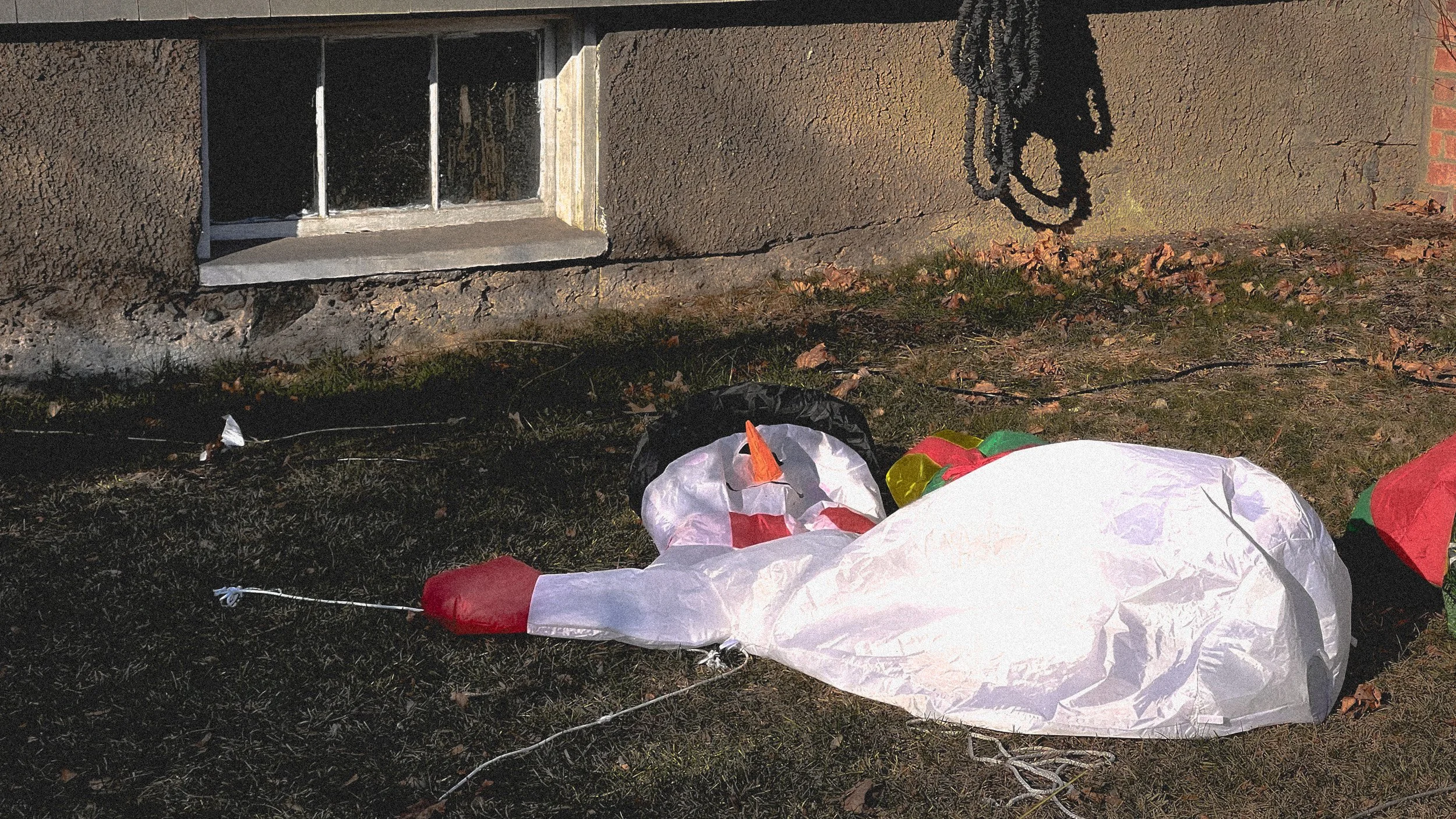 A holiday inflatable collapsed on the lawn — cheer deflated into a slumped, off-kilter heap.
