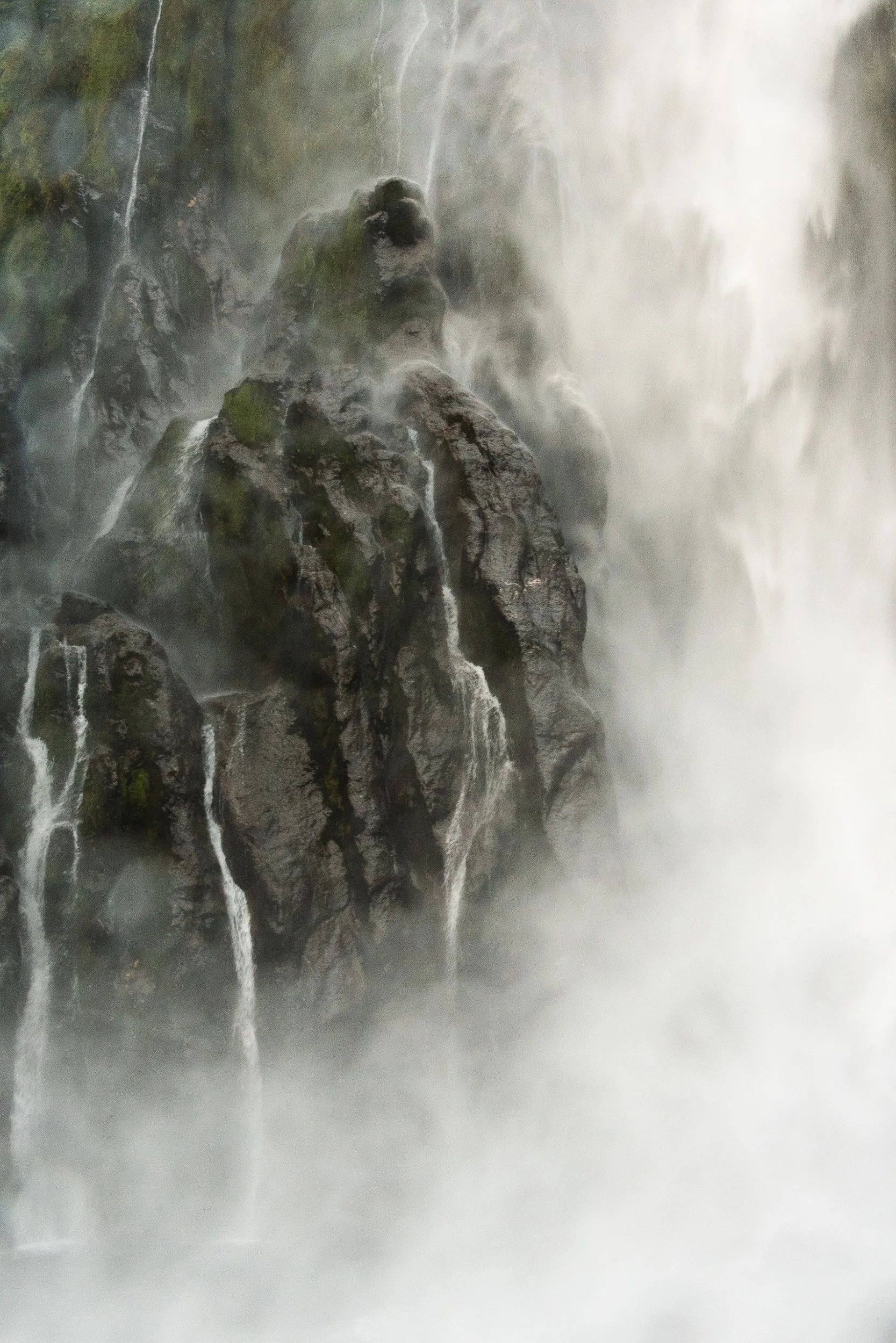 Close-up of a waterfall cascading over rocks with mist rising from the water.