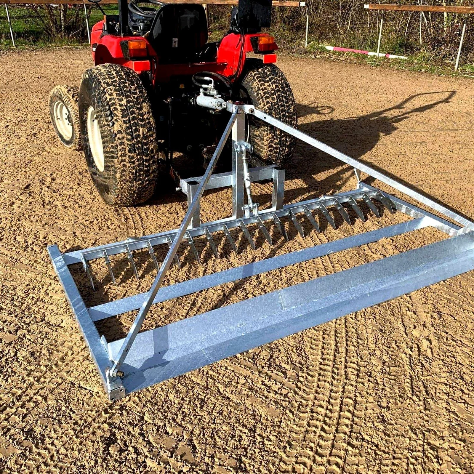Herse niveleuse attelée derrière un quad, utilisée pour l'entretien et le nivellement des sols équestres