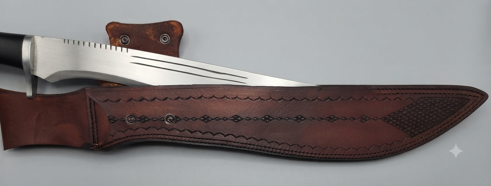 A large kitchen knife with a serrated edge partially inside a leather sheath with decorative stitching, placed on a flat surface.