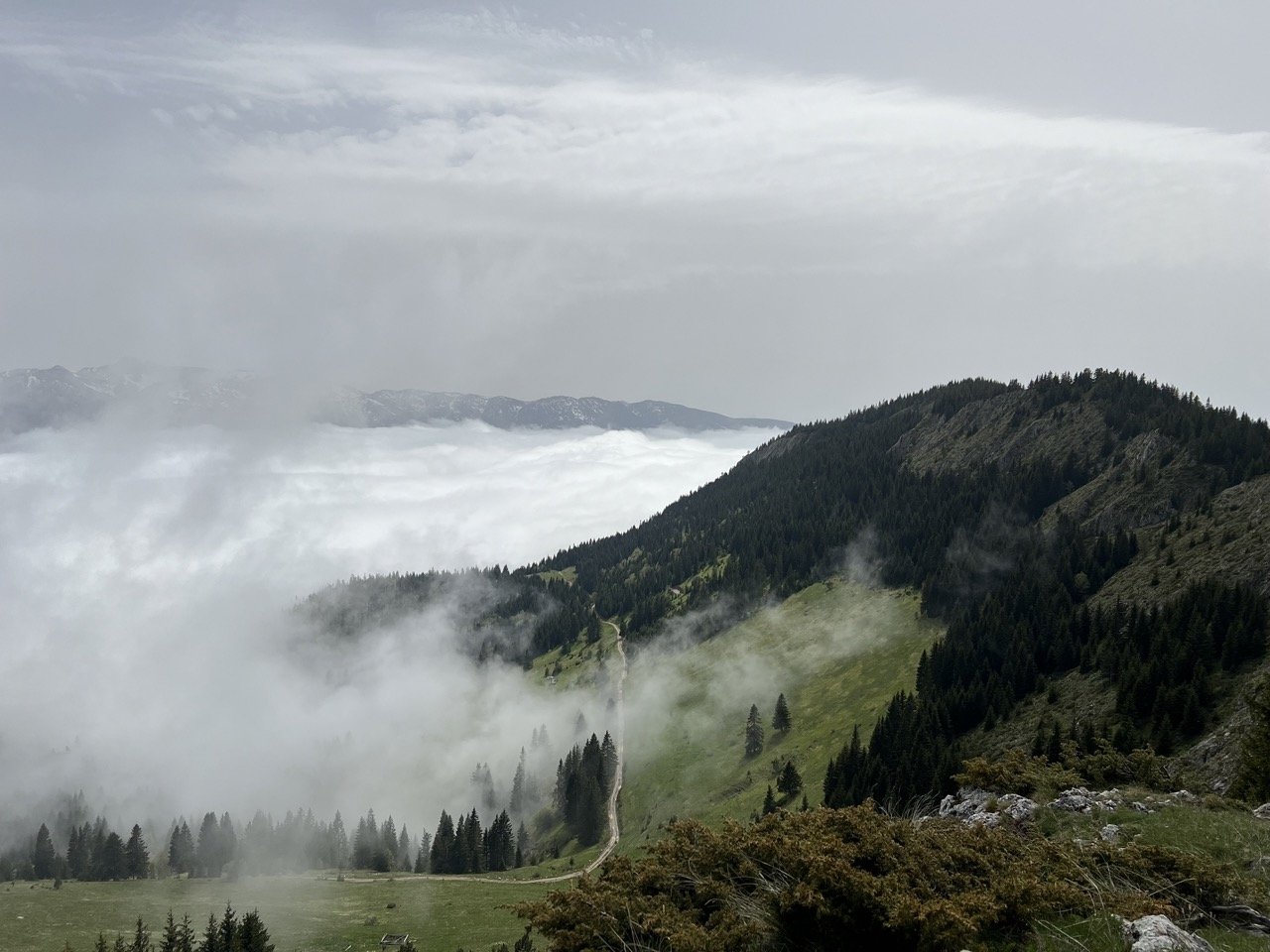 Green rolling hills and mountain peaks under a partly cloudy sky.