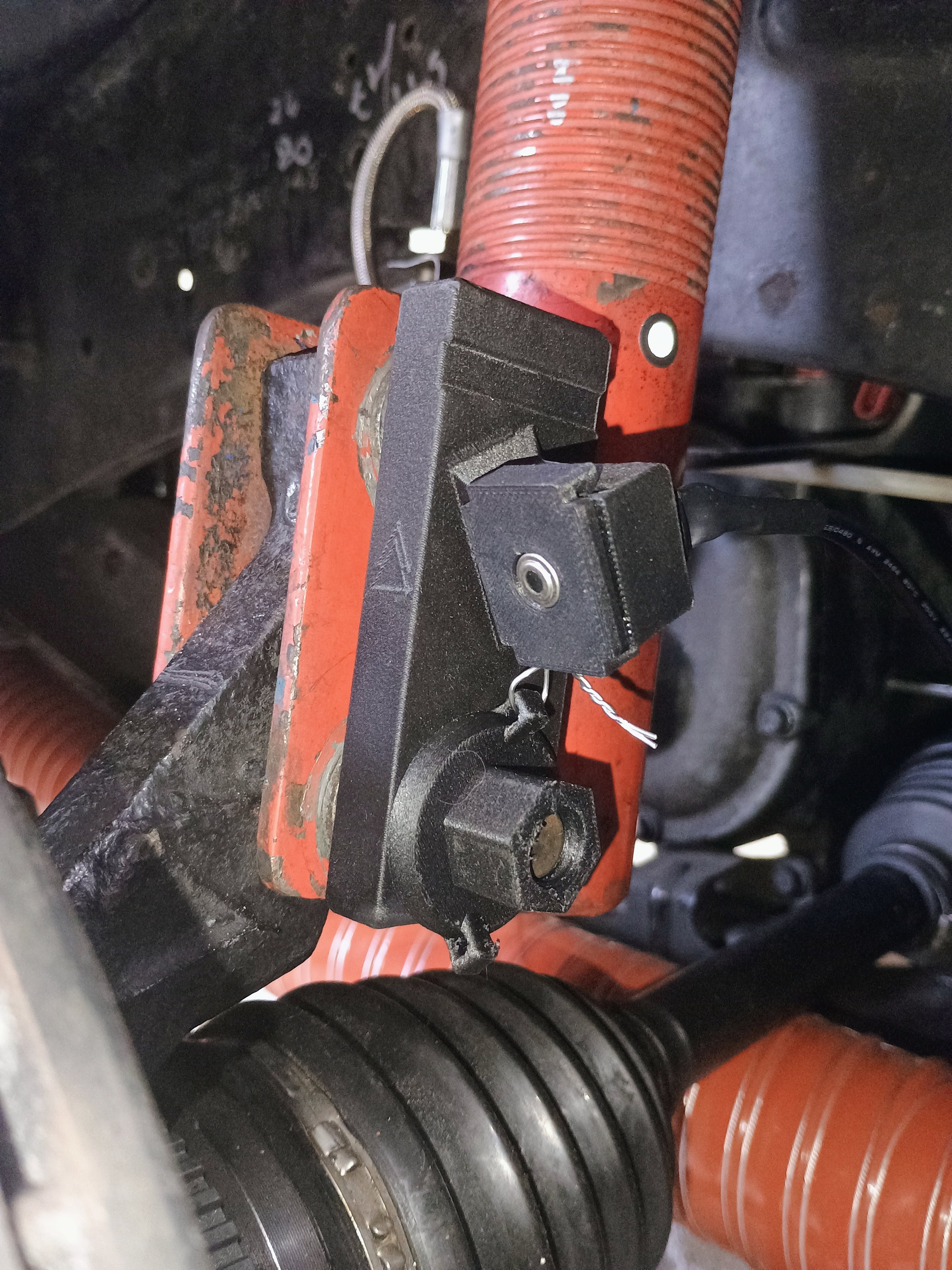 The brake Temp Sensor in place. The Sensor is attached with a custom designed housing and nut both made of PET-CF for strong thermal and chemical resistance. Plus some lock wire and zipties for good measure.