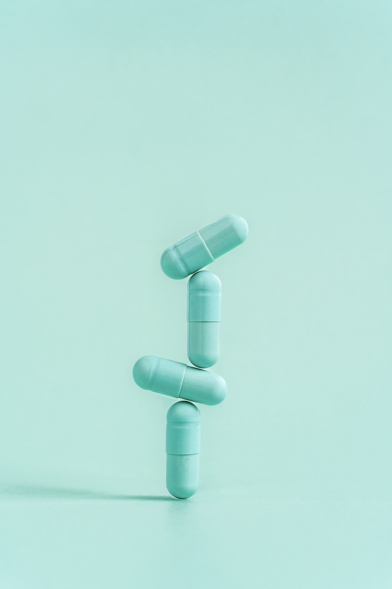 A human figure made of several blue capsules stacked vertically against a mince blue background.