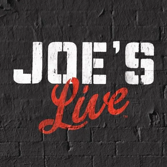 Sign on a brick wall reading "Joe's Live" with "Joe's" in white block letters and "Live" in red cursive.