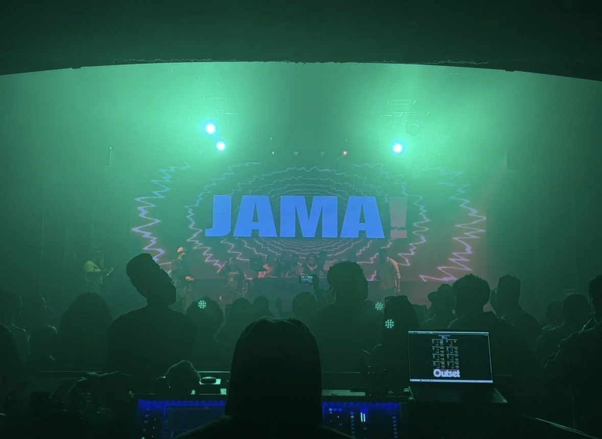 Concert scene with a large screen displaying 'JAMA!' and a crowd of people facing the stage, illuminated by green lights.