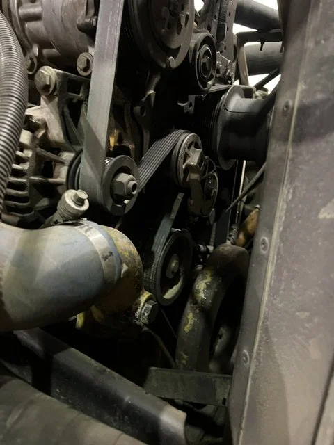A close-up view of an engine's timing belt and pulleys.