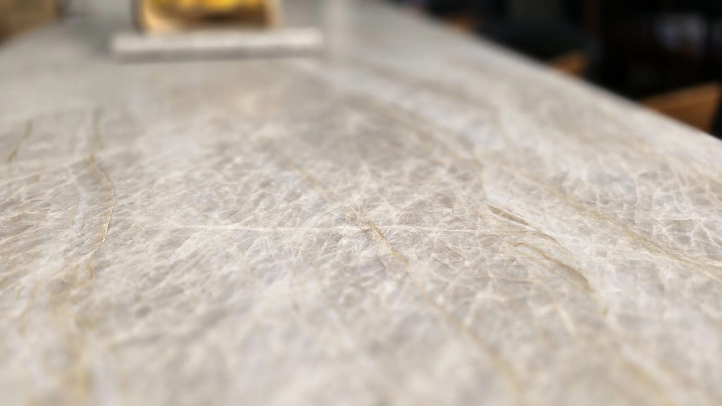 Close-up of a polished marble or granite countertop with a light beige and cream-colored pattern.